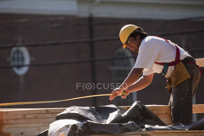 Carpenter using a tape measure at a construction site — Stock Photo