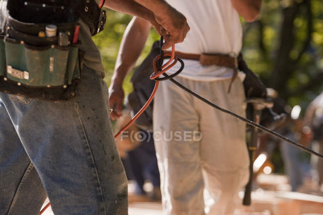 Carpintero desenredar el cable de alimentación en un sitio de construcción - foto de stock