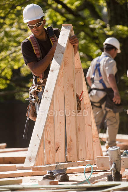 Carpinteiros segurando uma palheta de cobertura em um canteiro de obras — Fotografia de Stock