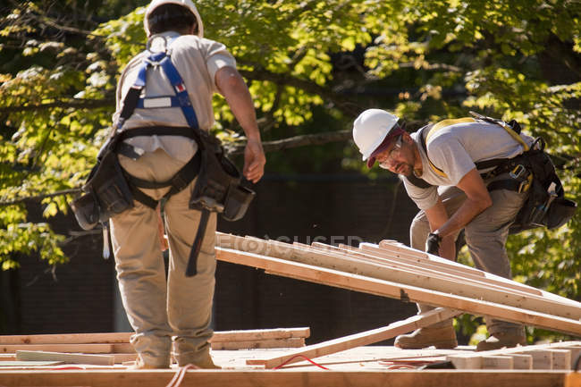 Carpinteros recogiendo un techo a dos aguas en un sitio de construcción - foto de stock