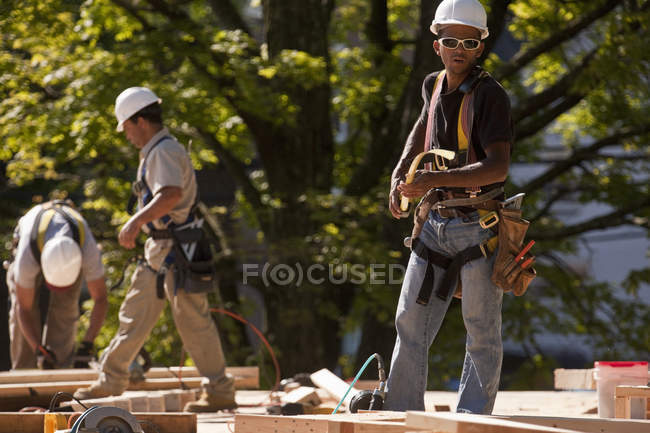Carpinteros usando cinta métrica en un sitio de construcción - foto de stock