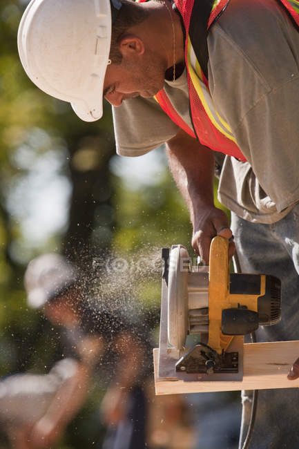 Carpinteiro com serra circular em canteiro de obras — Fotografia de Stock