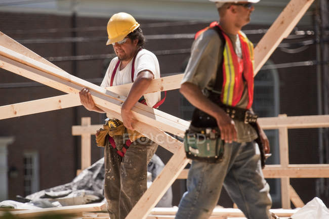 Zimmerleute tragen Holzbohlen auf einer Baustelle — Stockfoto