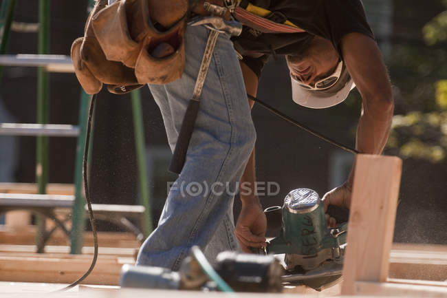 Carpinteiro com serra circular em canteiro de obras — Fotografia de Stock