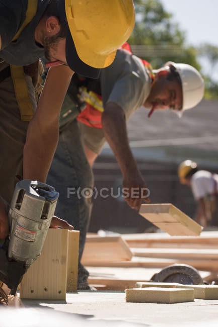 Carpenters working with nail gun and wood — Stock Photo