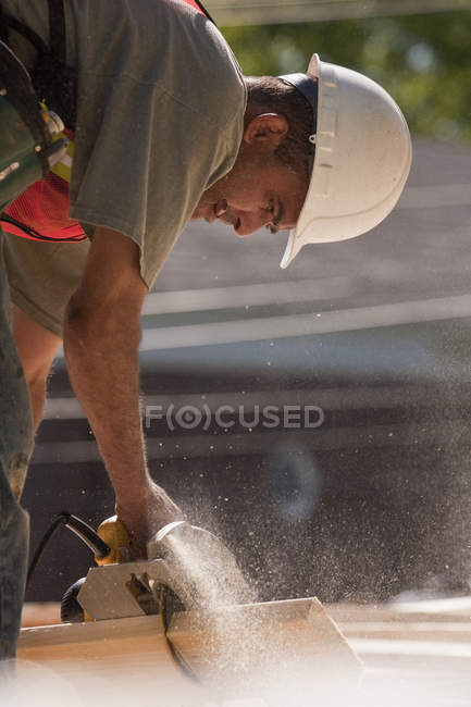 Charpentier utilisant une scie circulaire sur un chantier — Photo de stock