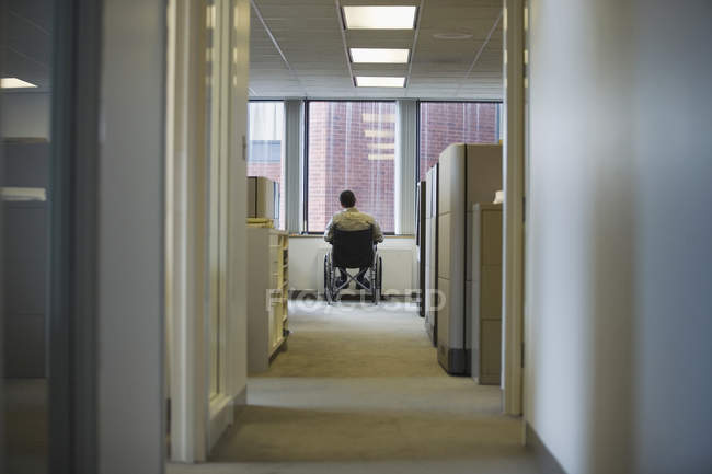 Вид сзади на человека, сидящего в инвалидном кресле в офисе — стоковое фото
