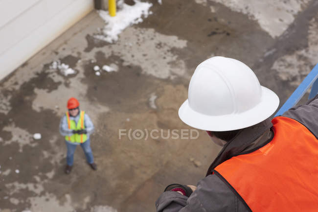 Engineer talking to managing engineer from an industrial tower — Stock Photo