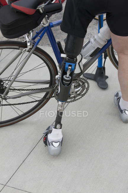 Mujer con una pierna protésica preparándose para una carrera en bicicleta - foto de stock