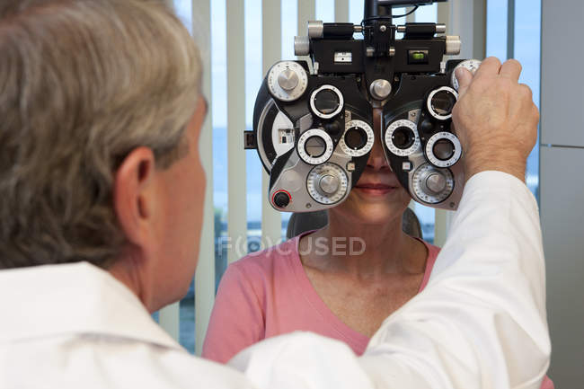 Ophthalmologist examining a womans eyes with a phoropter — Stock Photo