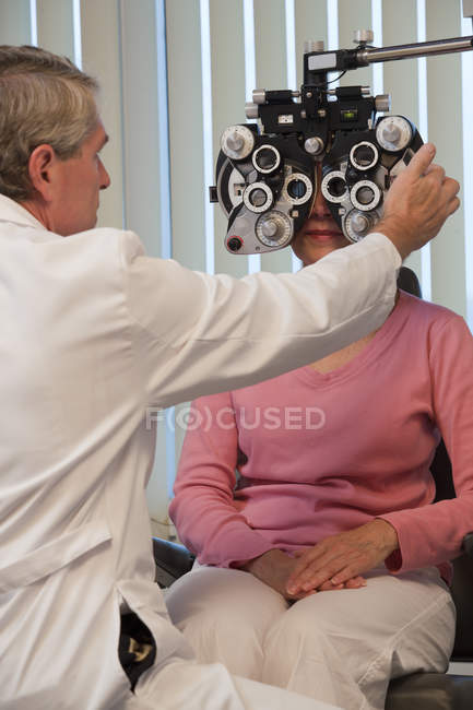 Oftalmologista examinando um olho de mulher com um phoropter — Fotografia de Stock