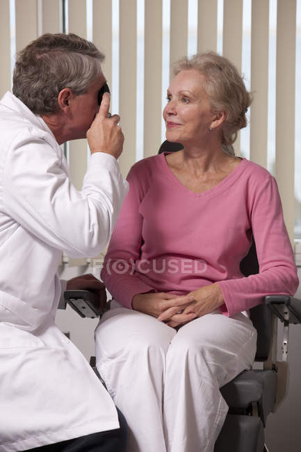 Ophthalmologist examining a womans eyes with a direct ophthalmoscope — Stock Photo