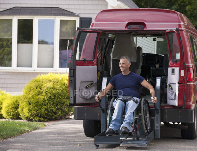 Mann mit Querschnittslähmung steigt im Rollstuhl in seinen barrierefreien Van — Stockfoto