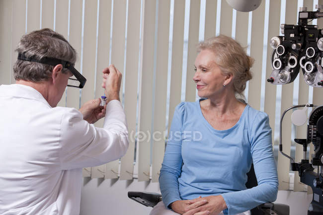 Oftalmólogo sosteniendo una inyección de Botox cerca de un paciente - foto de stock