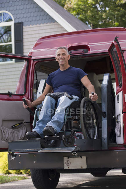 Людина з травмою спинного мозку в інвалідному візку потрапляє у його доступний фургон — стокове фото