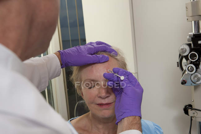 Офтальмолог впорскує ботокс пацієнту. — стокове фото