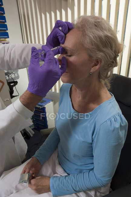 Офтальмолог делает инъекцию ботокса на лоб пациента — стоковое фото