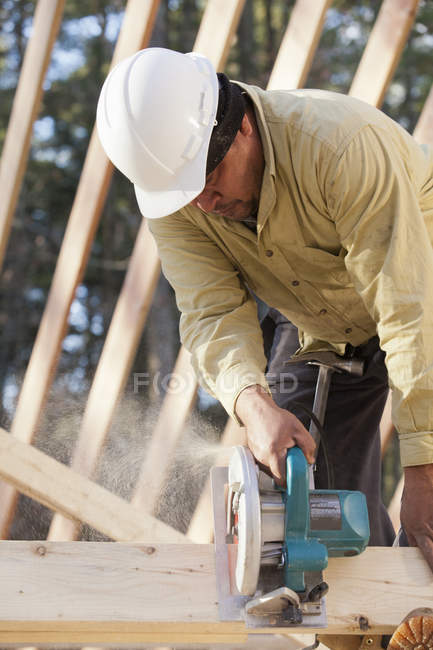 Carpenter using a circular saw on stud — Stock Photo