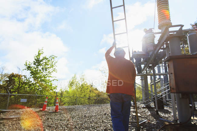 Energietechniker mit Leiter arbeitet an Hochspannungsverteilerstation — Stockfoto