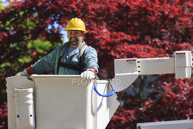 Power engineer in lift bucket working with power lines — Stock Photo
