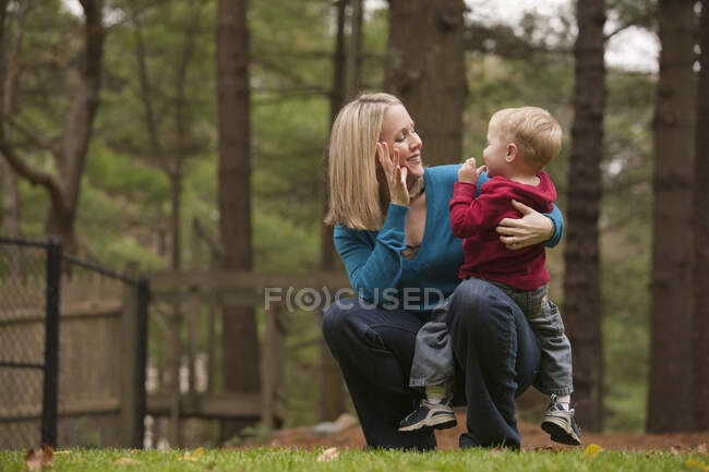 Mujer firmando la palabra 'Mami' en lenguaje de señas americano mientras se comunica con su hijo - foto de stock