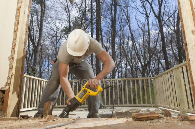 Hispanic carpenter using reciprocating saw to cut framing pieces for removal — Stock Photo