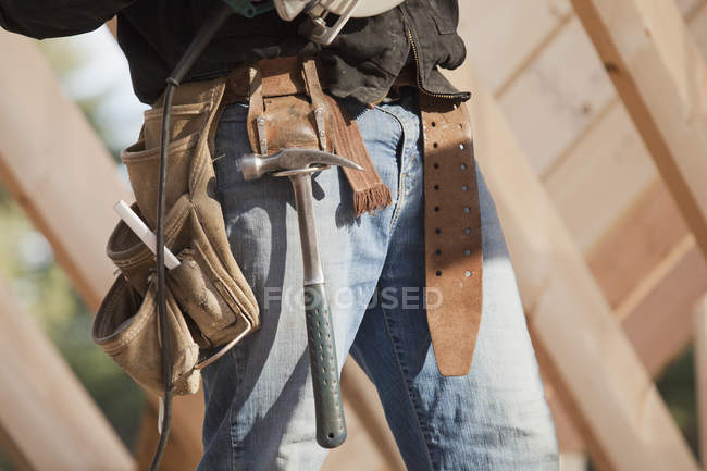 Carpinteiro com cinto de ferramentas em um canteiro de obras, imagem cortada — Fotografia de Stock