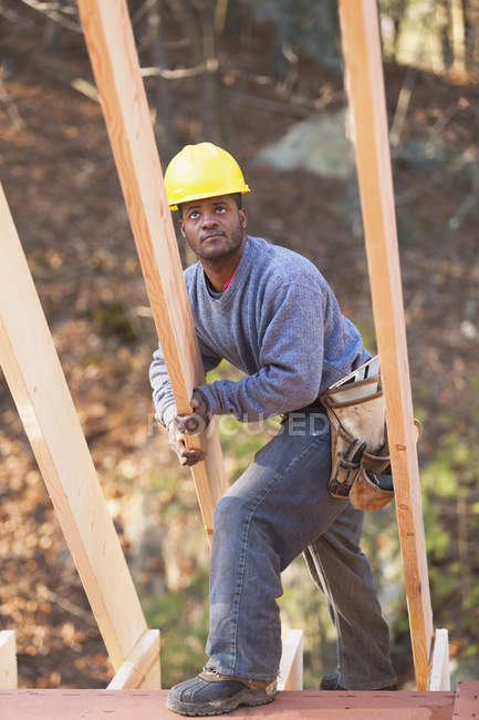 Carpintero colocando una viga para la construcción de casas - foto de stock