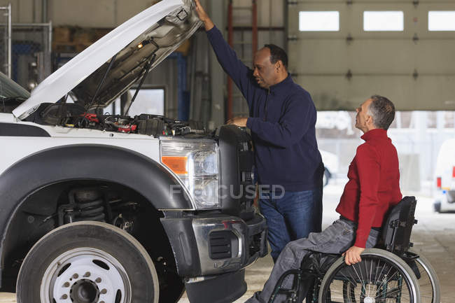 Automotive maintenance technician and supervisor with spinal cord injury in truck garage — Stock Photo