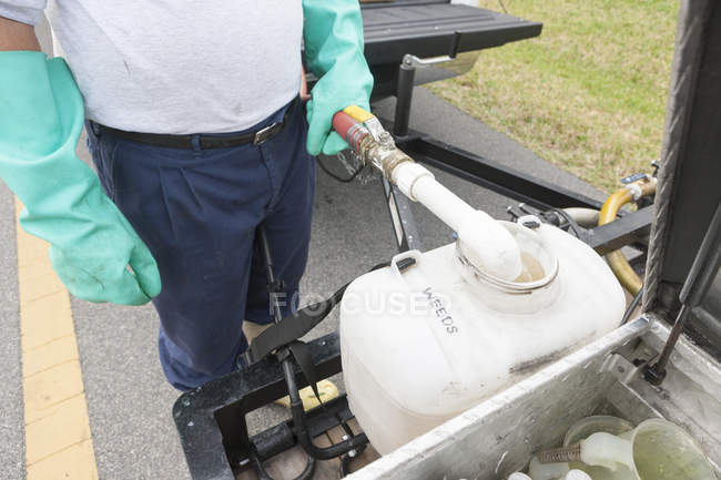 Técnico de controle de pragas adicionando água ao recipiente químico no caminhão — Fotografia de Stock