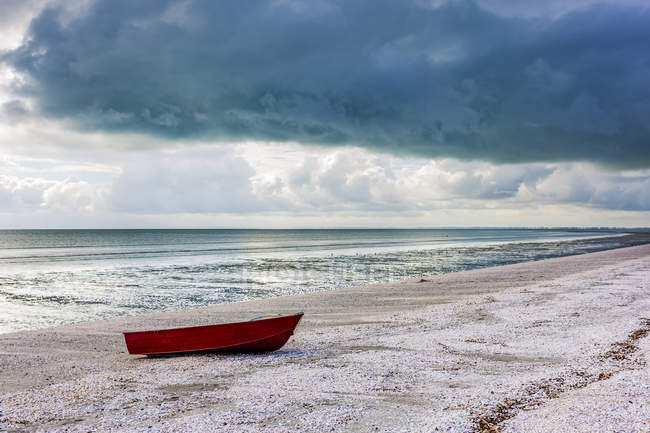 Red boat on shell beach; North Island, New Zealand — Stock Photo