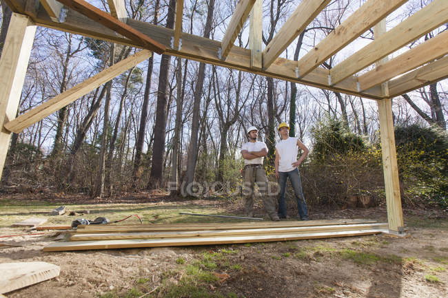 Carpinteros hispanos revisando construcción de cubierta - foto de stock