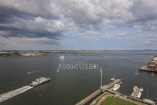 Barcos de cercanías en Boston Harbor con Logan Airport y Fan Pier, Boston, Massachusetts, EE.UU. - foto de stock