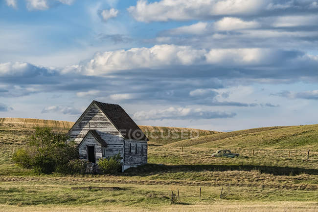 Igreja rural velha e abandonada resistiu aos anos nas pradarias e um carro antigo deixado no campo para trás; Val Marie, Saskatchewan, Canadá — Fotografia de Stock