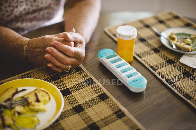 Mulher sênior com caso de pílula na mesa — Fotografia de Stock