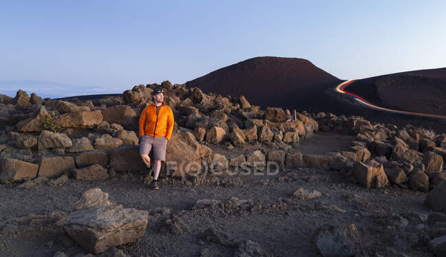 Человек стоит против прочных скал над облаками на Халеакале; Мауи, Гавайи, Соединенные Штаты Америки — стоковое фото