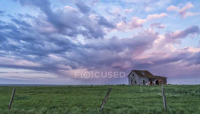 Old farmstead on the prairies under glowing storm clouds at sunset; Val Marie, Alberta, Canada — Stock Photo