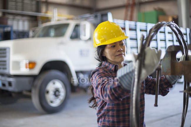Engenheira de energia feminina com cabo de alimentação na garagem de serviço — Fotografia de Stock