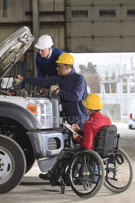 Ingegneri di centrali elettriche uno con lesione del midollo spinale revisione manutenzione camion utilità — Foto stock