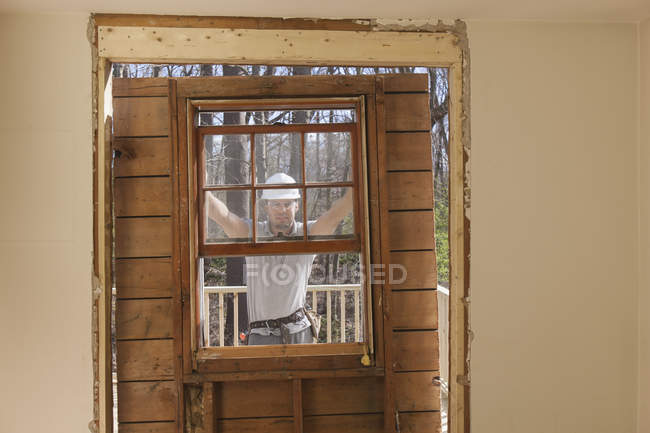 Charpentier hispanique enlevant l'accès de porte nouvellement coupé au pont sur la maison — Photo de stock