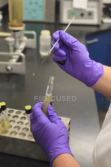 Lab technician using flame test probe to gather sample from vile — Stock Photo