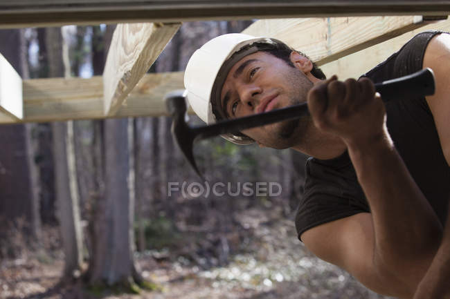 Hispanic carpenter hammering deck joist — Stock Photo