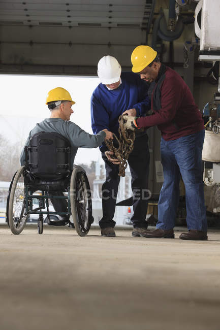 Wartungsbeauftragter einer mit Querschnittslähmung bewegt Abschleppkette in Nutzfahrzeug-Garage — Stockfoto
