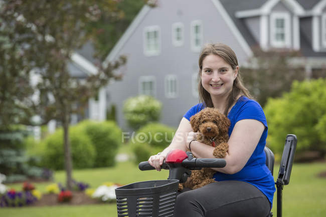 Молодая женщина с церебральным параличом катается на скутере со своей собакой — стоковое фото