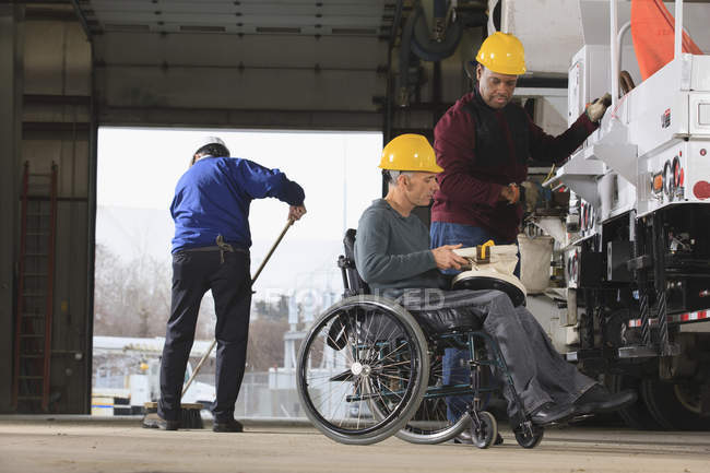 Maintenance supervisors, one with a spinal cord injury, cleaning utility garage and loading new truck with supplies — Stock Photo