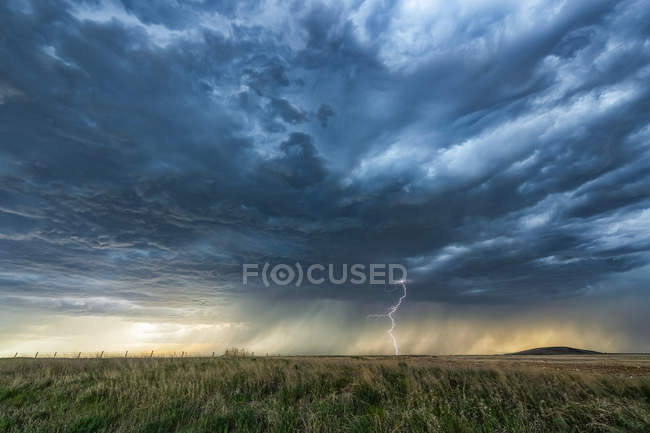 Rainfall in the distance on the prairies under ominous storm clouds; Saskatchewan, Canada — Stock Photo