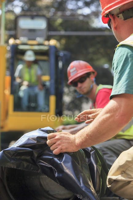 Trabajadores de la construcción se preparan para la excavadora para levantar el agua principal en su lugar - foto de stock