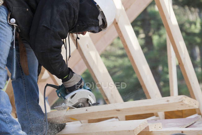 Carpinteiro usando uma serra circular fazendo corte chanfrado — Fotografia de Stock