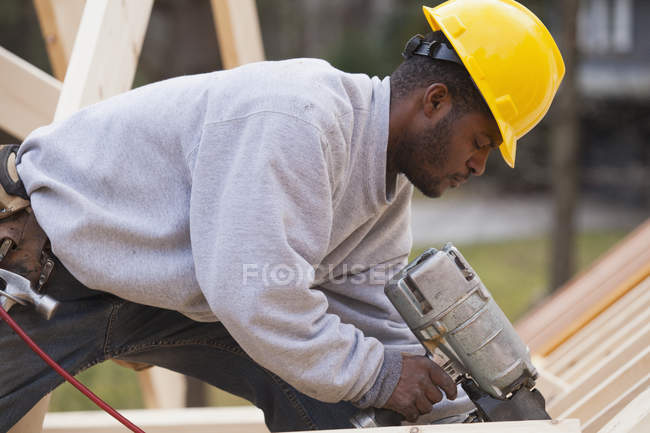 Carpenter nailing at roof level — Stock Photo