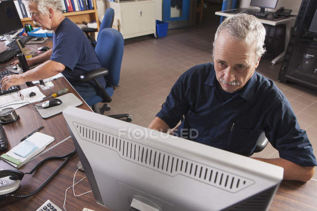 Два инженера на компьютерах запускают установку очистки воды в рамках программы надзорного контроля и сбора данных — стоковое фото